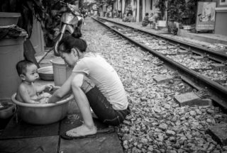 Black and White photo by Graeme Heckels Hanoi Street Photography Life on The Train Tracks Baby Bathtime
